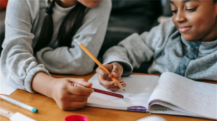 Youth helping young child with homework.
